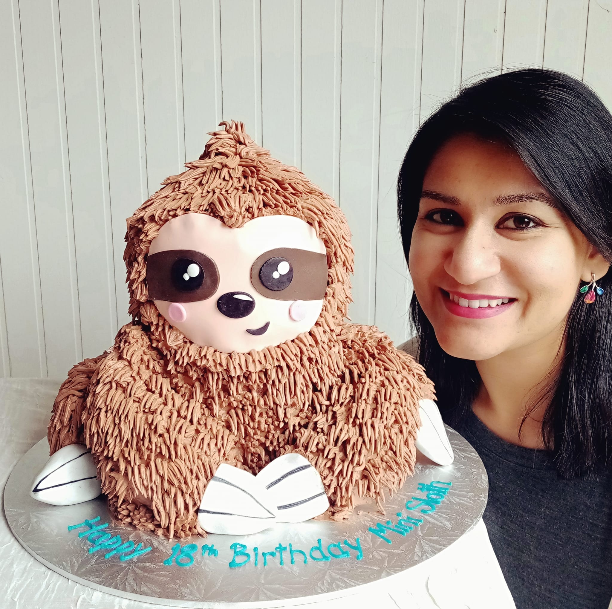 The Cake Lady beside a handcrafted sloth celebration cake